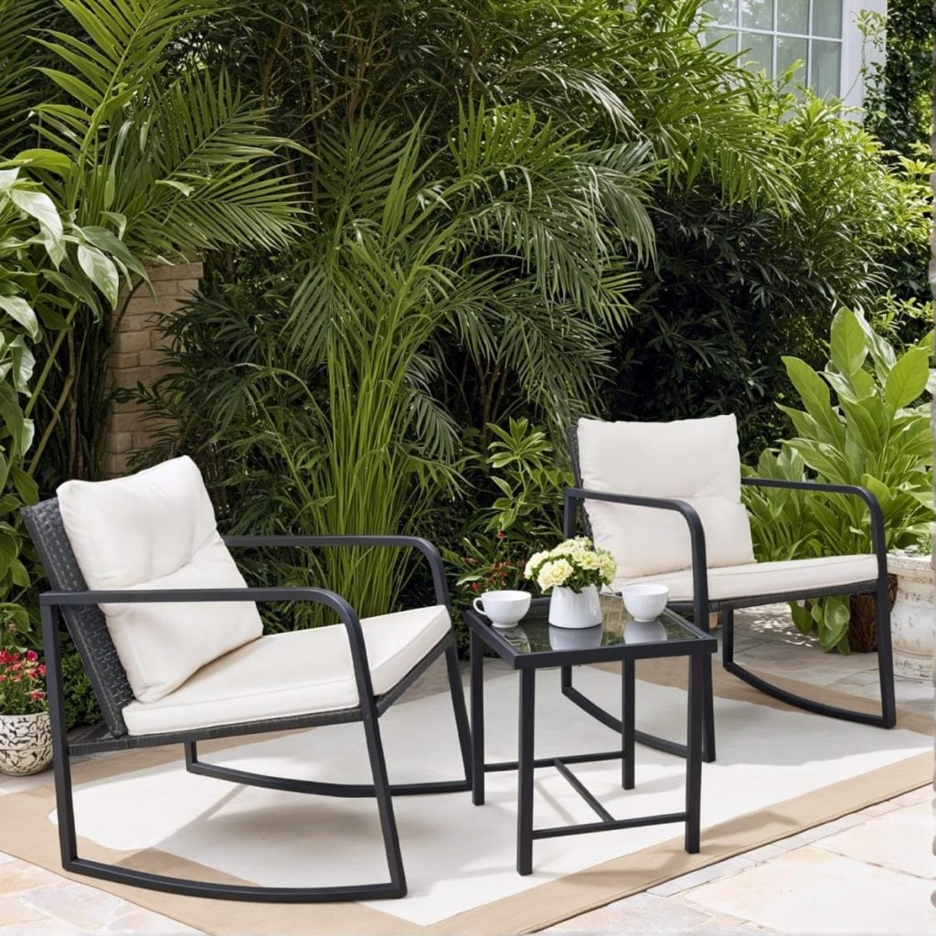 Two cushioned patio chairs and a small table with a flower vase and cups are set on a rug outdoors, surrounded by lush green plants&mdash;perfect for relaxing or entertaining during the Amazon Big Spring Sale.