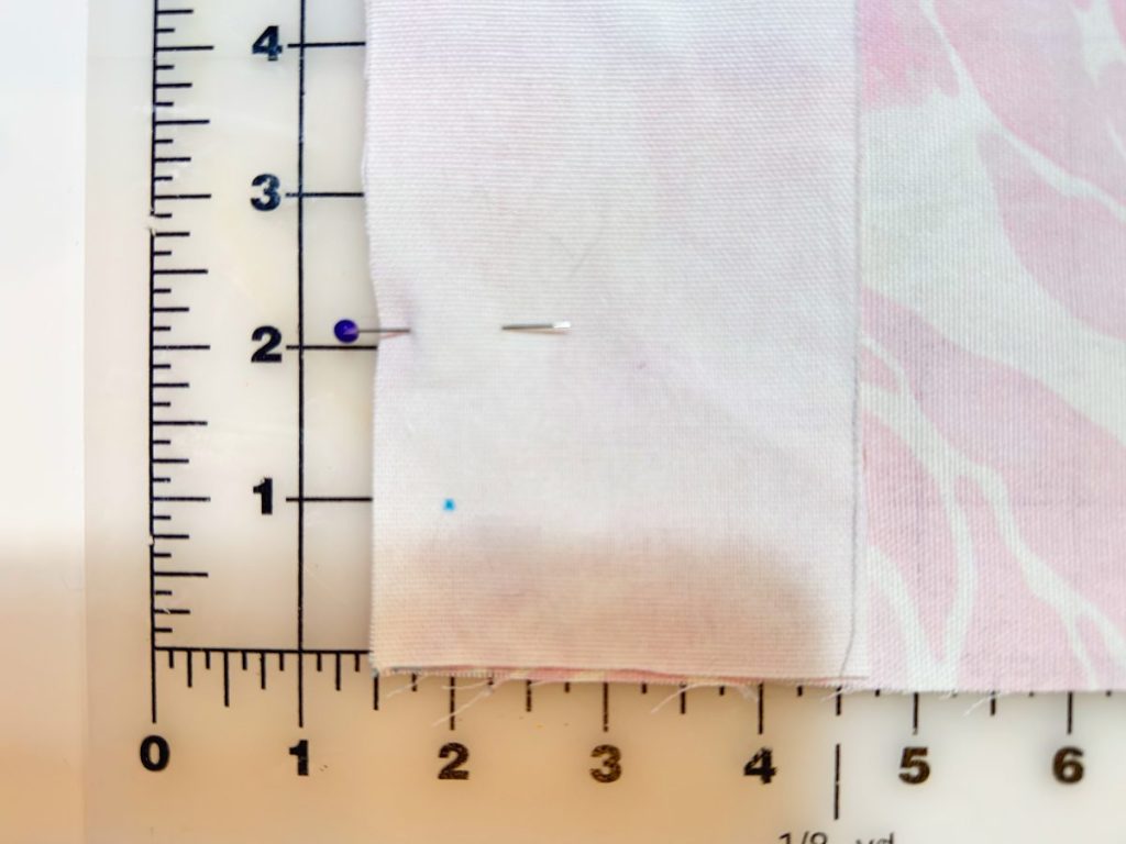 A piece of fabric is pinned and aligned on a ruler grid, showing measurements in inches along the edges.