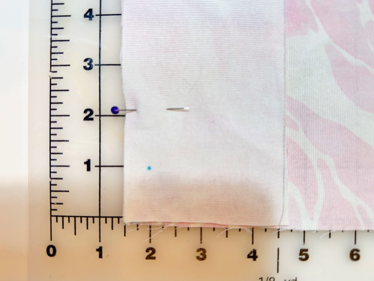 A piece of fabric is pinned and aligned on a ruler grid, showing measurements in inches along the edges.
