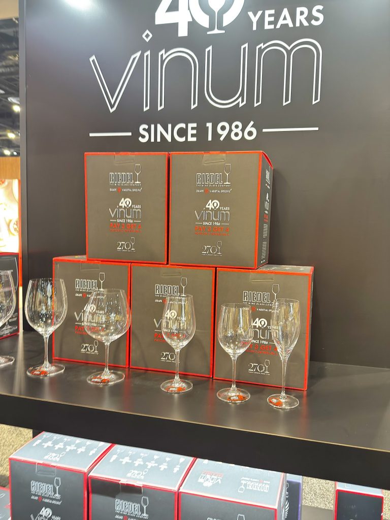 Display of Riedel Vinum wine glasses and boxed sets on shelves, with signage above reading "40 years Vinum since 1986.