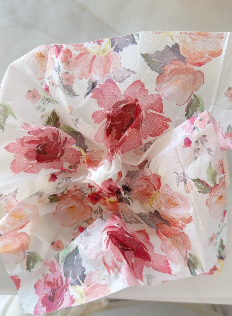 A floral-patterned paper napkin is crumpled at the center, with pink and red flowers printed on a white background.