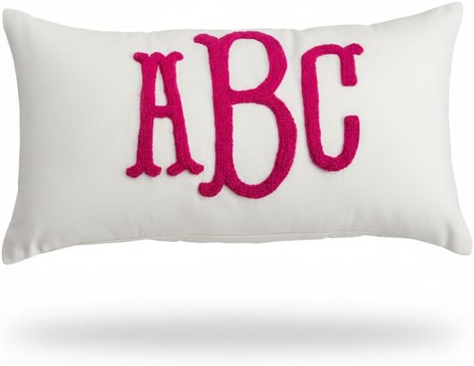 Rectangular white pillow with large, bold, pink embroidered letters "ABC" on the front.