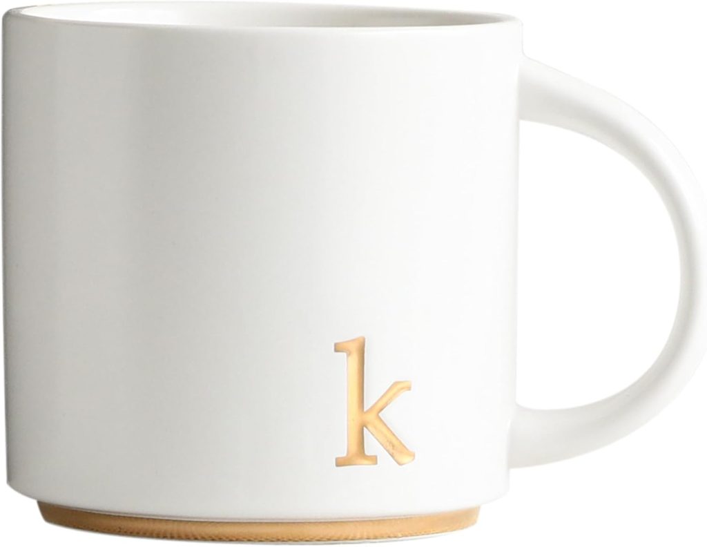 White ceramic mug with a gold lowercase letter "k" and a gold accent along the bottom edge.