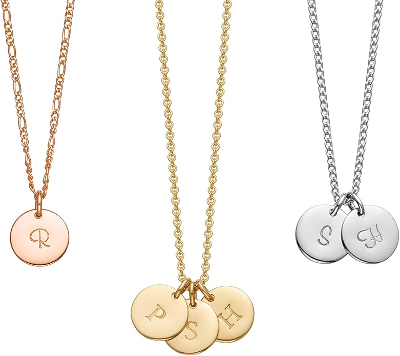 Three necklaces with round letter-engraved pendants: one rose gold with "R", one gold with "P", "S", "H", and one silver with "S" and "H" engravings.