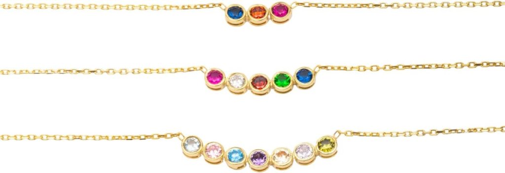 Three gold chain necklaces, each featuring a row of colorful round gemstones set in gold bezels, displayed against a white background.