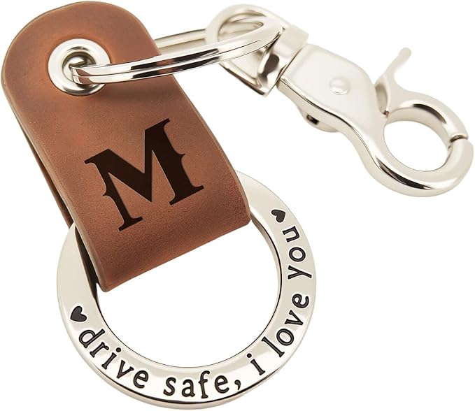 A brown leather keychain with the letter "M" engraved and a metal ring inscribed with the words "drive safe, I love you" and heart symbols.