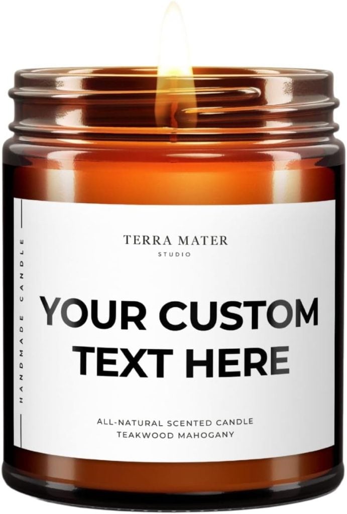 Brown glass candle jar with a white label displaying placeholder text "YOUR CUSTOM TEXT HERE," perfect for adding a name for your home and a warm, inviting glow with its lit flame on top.