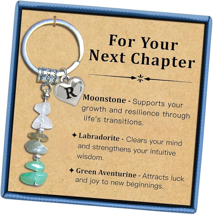 A keychain with a heart-shaped "R" charm and gemstone chips is displayed in a box with text describing the benefits of moonstone, labradorite, and green aventurine.