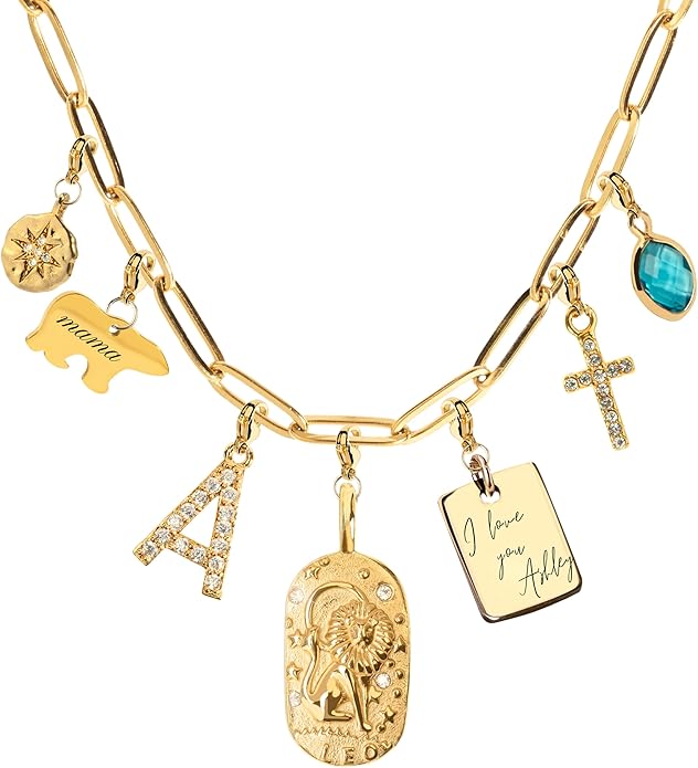 Gold chain necklace with various charms, including a compass, "mama" bear, letter A, religious pendant, "I love you Abby" tag, cross, and blue gemstone.