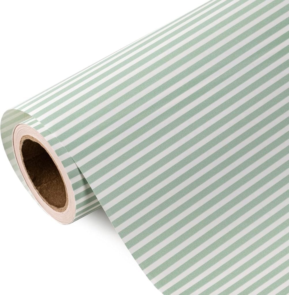 A roll of paper with diagonal green and white stripes, partially unrolled, featuring a pattern inspired by handpainted shells.