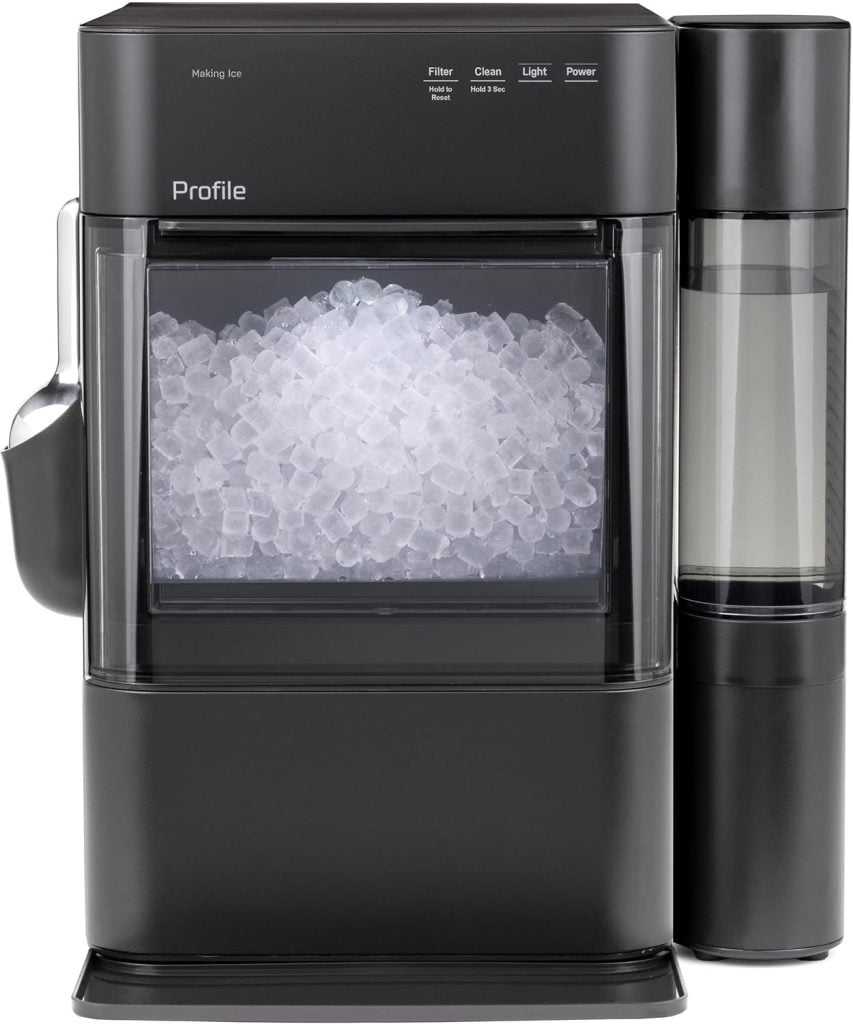 A black countertop ice maker filled with clear nugget ice, featuring a water reservoir on the right side and an ice scoop attached to the left.