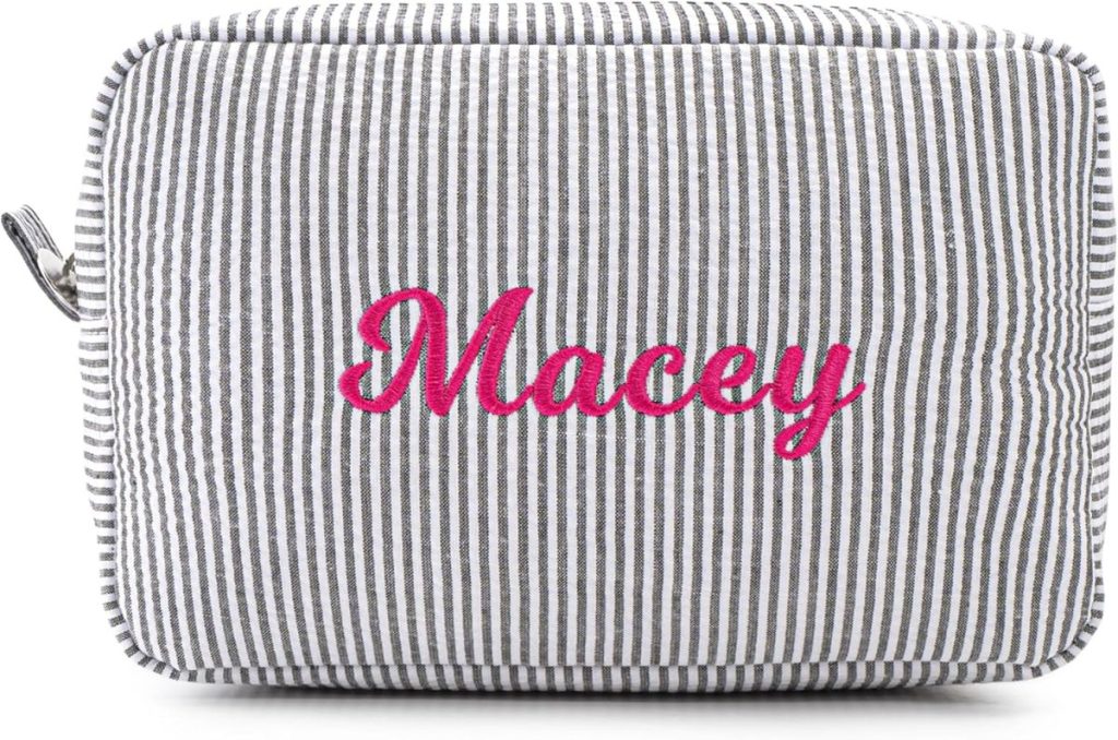 A rectangular, gray and white striped pouch with the name "Macey" embroidered in pink cursive letters on the front.