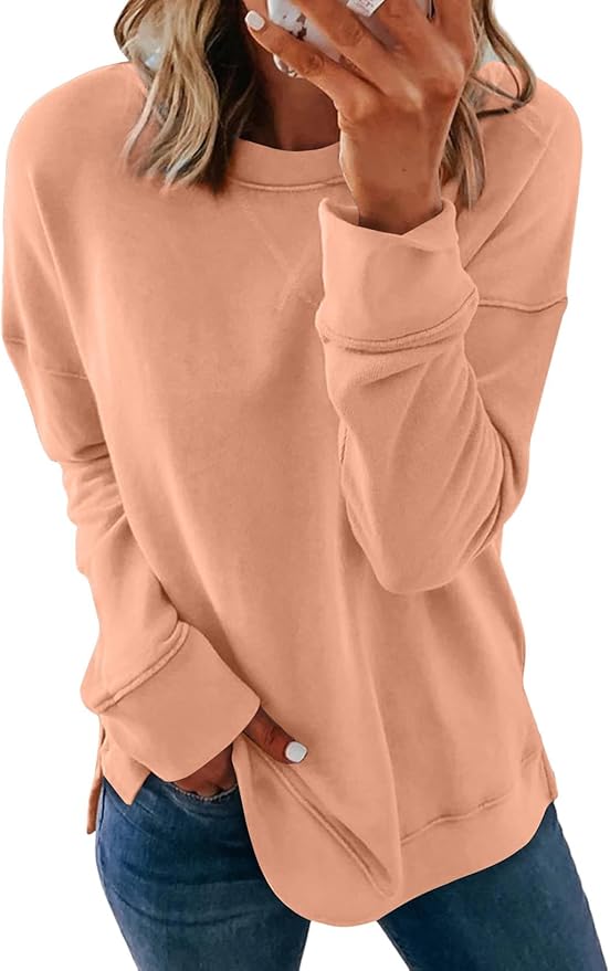 Woman wearing a light peach long-sleeve sweatshirt and blue jeans, with her hand near her face and nails painted white—perfect for a relaxed day of summer crafting.