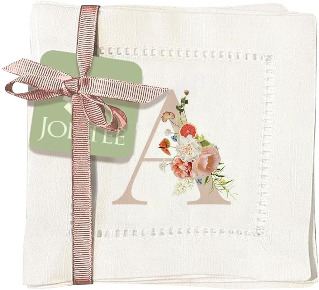 A white handkerchief with a pink ribbon and tag, featuring the letter "A" decorated with flowers printed in the corner, perfect as embroidered cocktail napkins for elegant gatherings.
