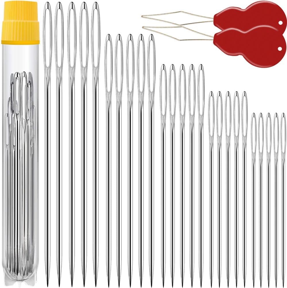 A set of metal sewing needles in various sizes, a yellow-topped storage tube, and two red needle threaders displayed on a white background.