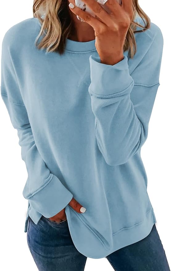 A person wearing a light blue long-sleeve sweatshirt and blue jeans, with one hand in a pocket and the other near their face, looks inspired—perhaps dreaming up new summer crafting projects.