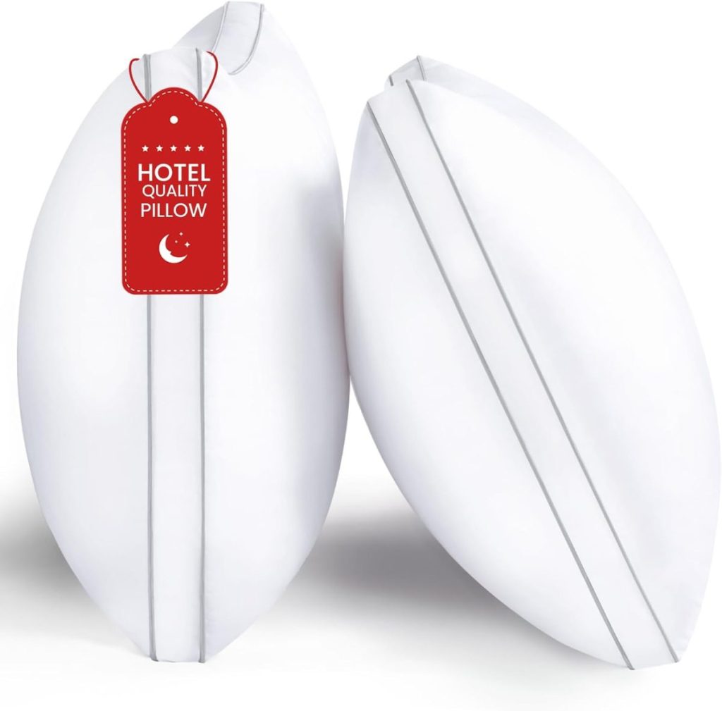 Two white pillows with grey piping, one with a red tag that reads "Hotel Quality Pillow," standing upright against a plain white background.