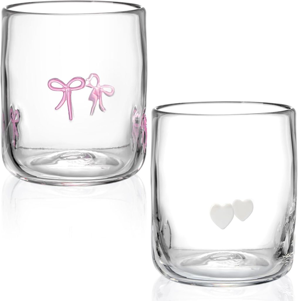 Two clear glass tumblers; one features pink bow designs, the other has two small white hearts. Pair them with our embroidered cocktail napkins for an elegant and coordinated touch to your next gathering.
