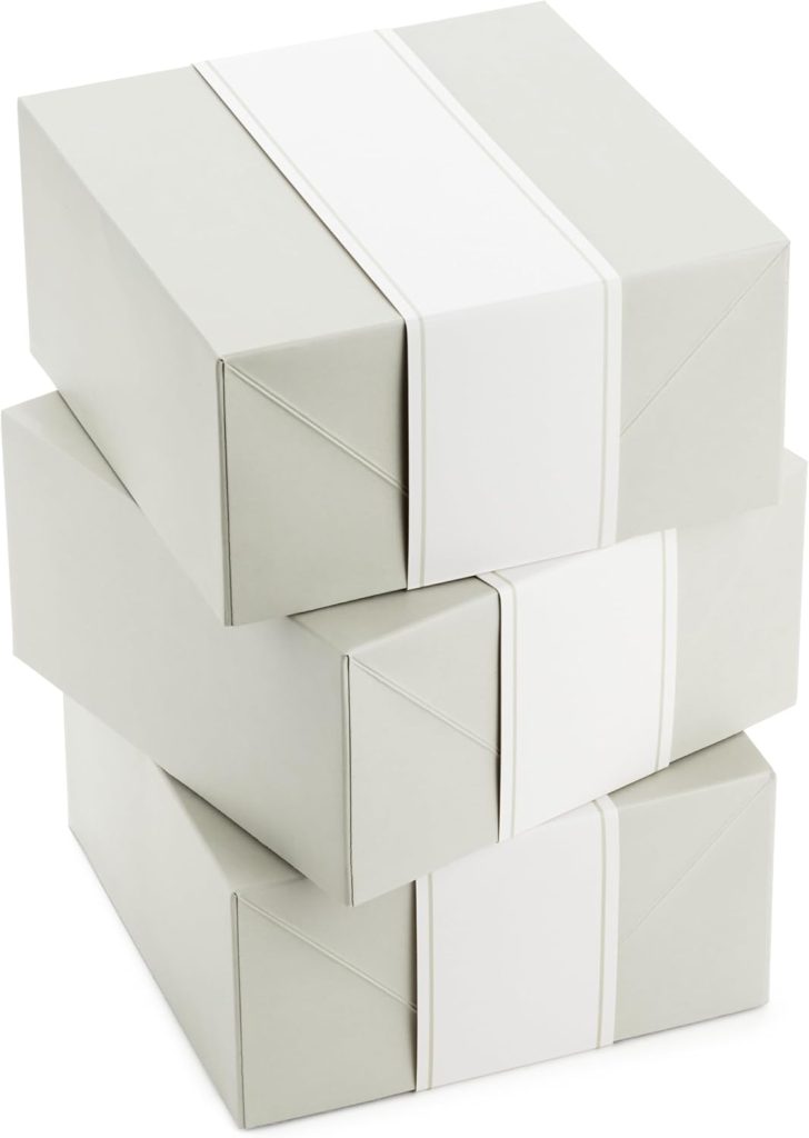 Three light gray gift boxes stacked on top of each other, each box wrapped with a plain white band and adorned with elegant wax seals.