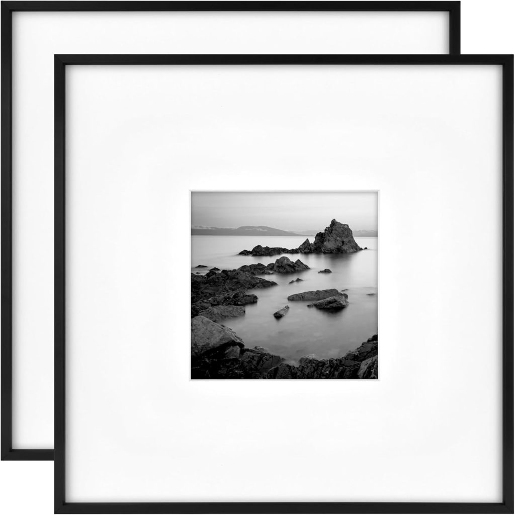 Two black-framed square wall art pieces, inspired by Theo of Golden Book Club, display black-and-white photographs of rocky seashores with a minimalist white mat.