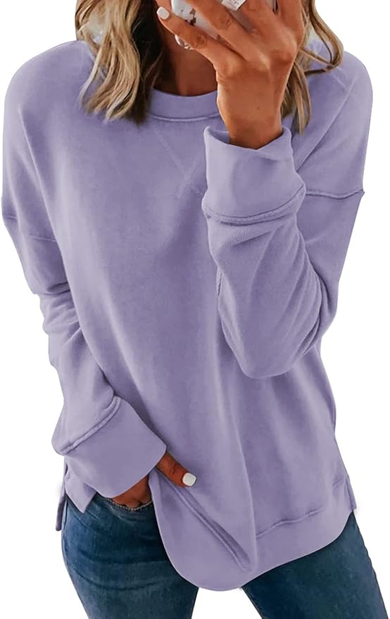 A woman wearing a loose-fitting light purple sweatshirt and blue jeans, with one hand in her pocket and the other touching her face, takes a break from summer crafting.