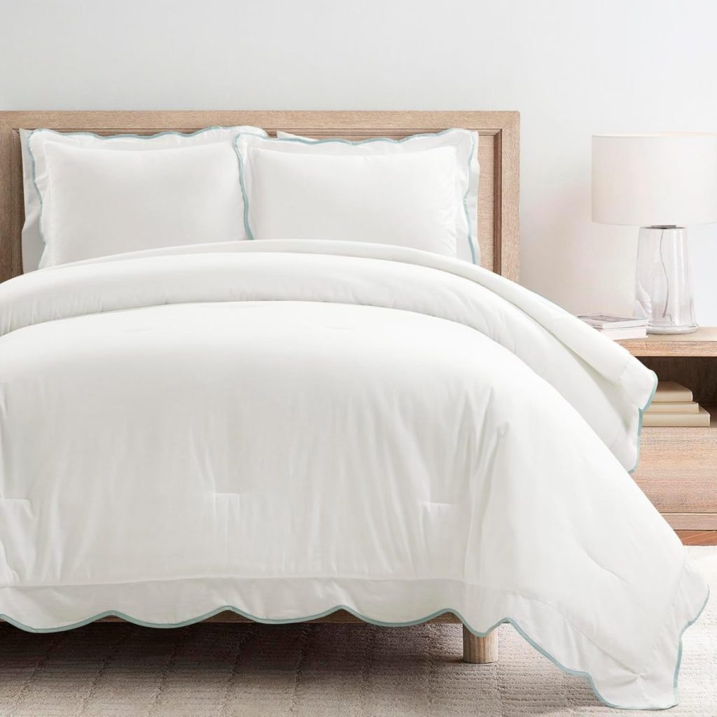 A neatly made bed with white bedding and two pillows, a wooden headboard, and a bedside table with a lamp, all set on a light-colored rug—perfect for refreshing your space now that summer is coming.