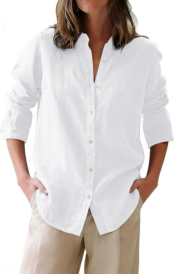 A person wearing a loose-fitting white button-up shirt with long sleeves and beige pants, standing with hands in pockets against a plain background.