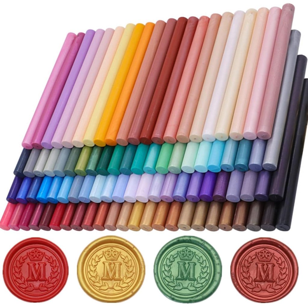 A variety of colorful wax sealing sticks arranged in rows, with four wax seals in red, gold, green, and brown displayed at the bottom&mdash;each embossed with the letter "M.
