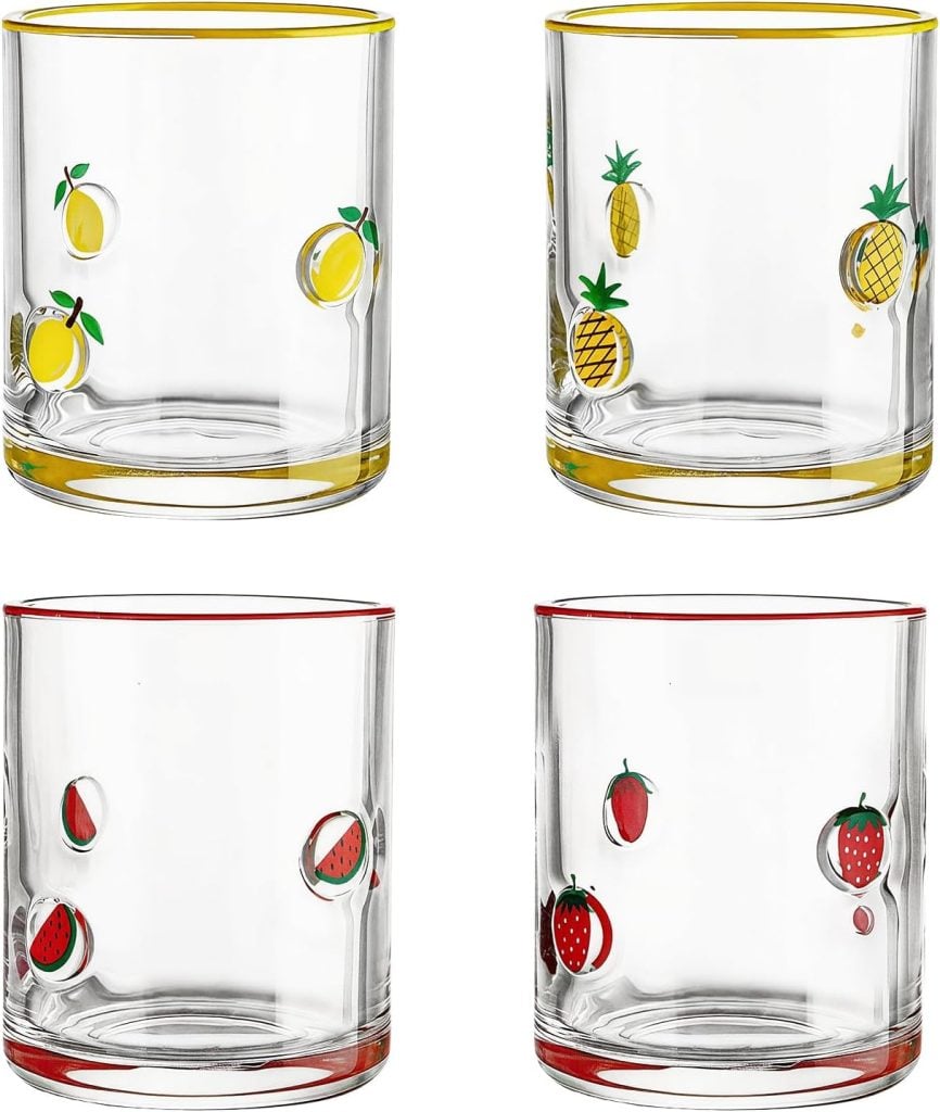 Four clear glass tumblers, each decorated with different fruit illustrations&mdash;lemons, pineapples, watermelons, and strawberries&mdash;with colored rims matching the fruit themes, pair beautifully with embroidered cocktail napkins for a charming table setting.