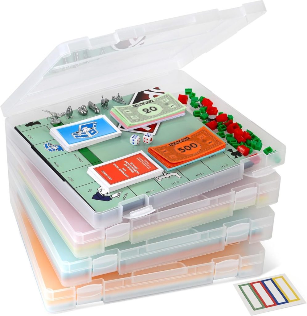 Clear plastic storage case holding a Monopoly board, money, cards, dice, houses, hotels, and metal game tokens, with other colored cases stacked underneath.