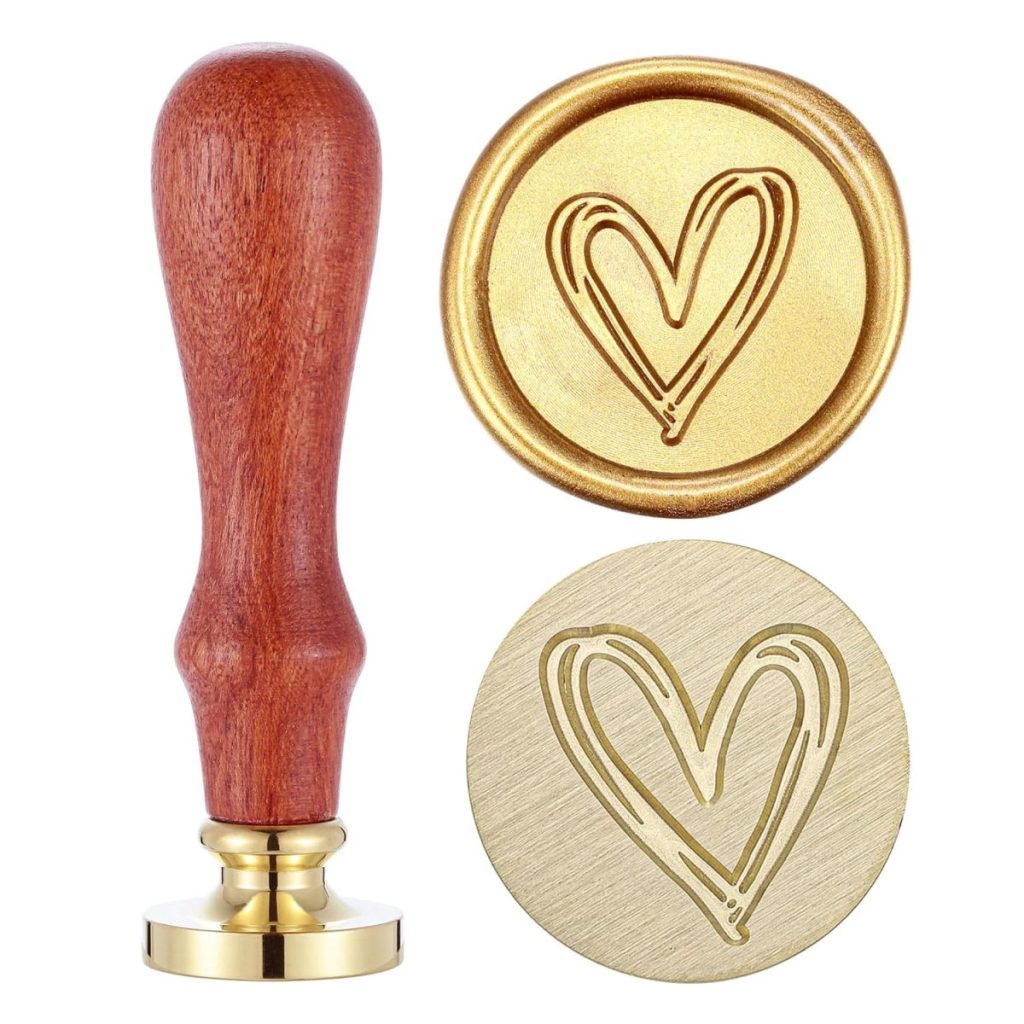 A wooden-handled brass wax seal stamp and two impressions, each showing a simple heart outline design&mdash;perfect for adding a charming touch to your wax seals.