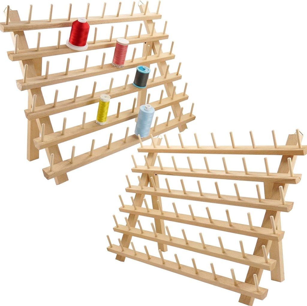 Two wooden thread racks, each with multiple rows of pegs, hold several spools of thread in various colors; one rack is empty.