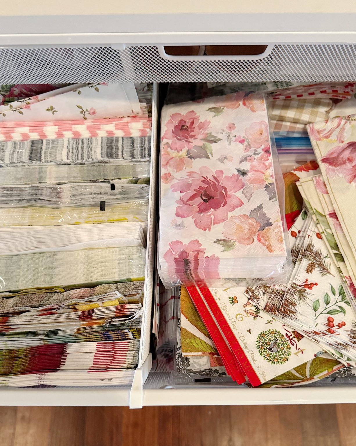 A drawer filled with neatly organized patterned napkins, including floral, striped, and holiday-themed designs.