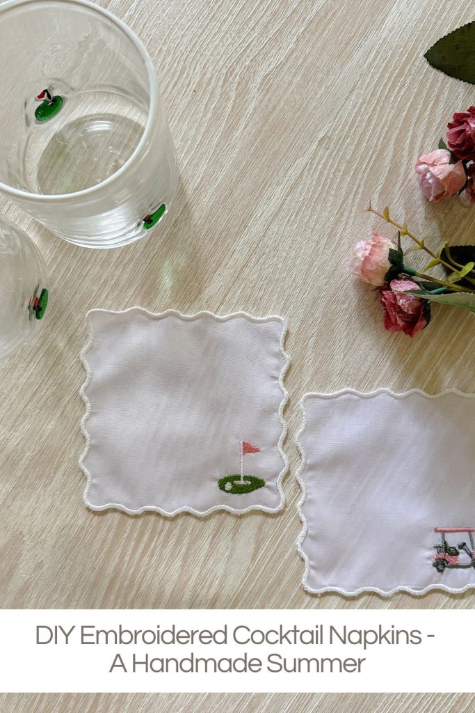 Two embroidered cocktail napkins with golf and airplane designs beside glasses and pink flowers on a light wooden surface. Text reads: "DIY Embroidered Cocktail Napkins - A Handmade Summer.