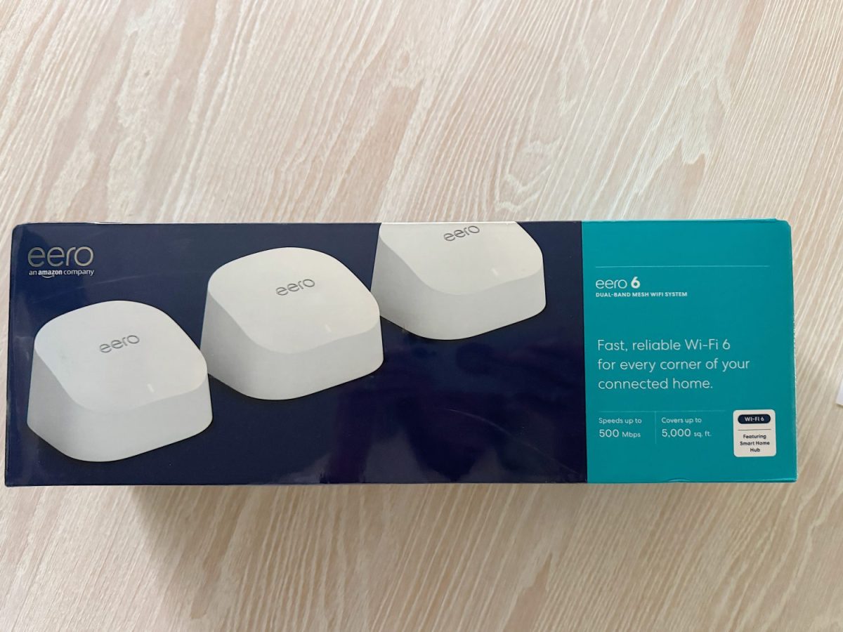 Box of eero 6 dual-band mesh Wi-Fi system with three devices, labeled for speeds up to 500 Mbps and coverage up to 5,000 sq. ft., on a light wood surface.