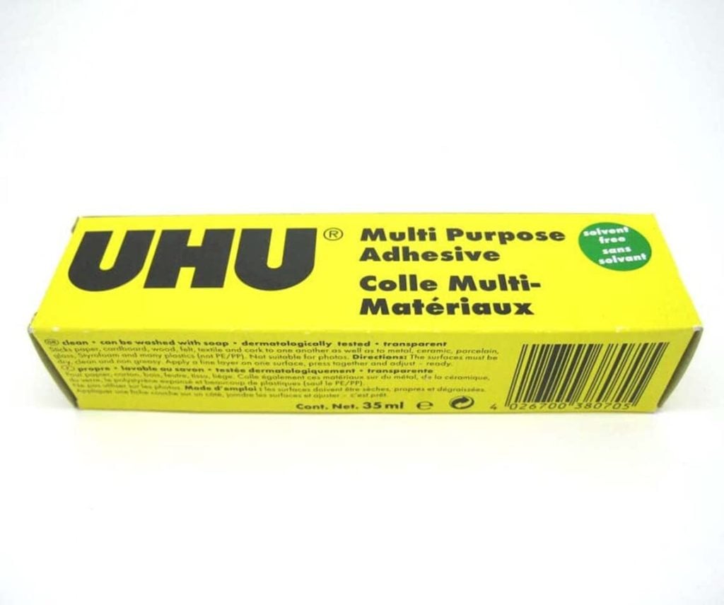 A yellow box of UHU Multi Purpose Adhesive, 35 ml, with text in English and French. The label notes it is solvent-free and suitable for various materials.