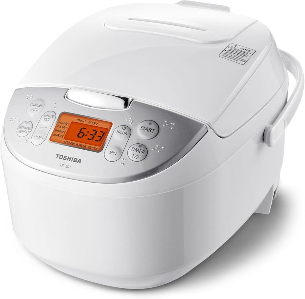 A white Toshiba electric rice cooker with a digital display and various control buttons on the front panel.