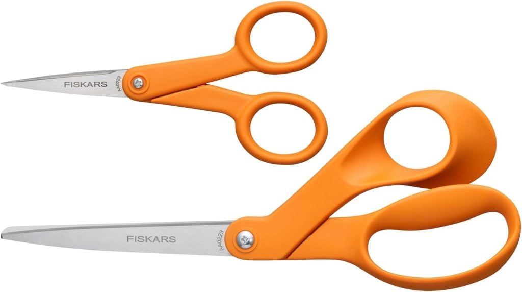 Two pairs of Fiskars craft tools scissors with iconic orange handles, one small and one large, positioned against a white background.