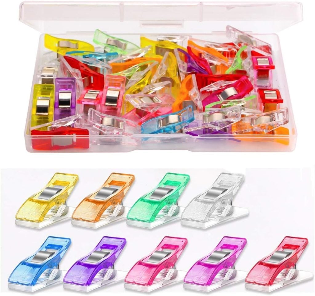 A plastic box containing multiple colorful sewing clips, with eight individual clips in various colors displayed in a row below the box.