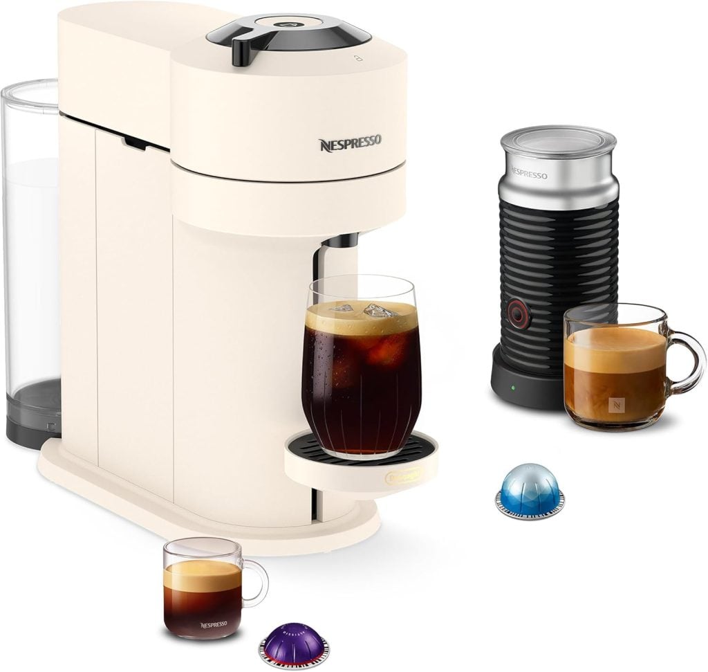 A Nespresso coffee machine with a glass of iced coffee, a milk frother, two cups of coffee, and three coffee pods displayed on a white background.