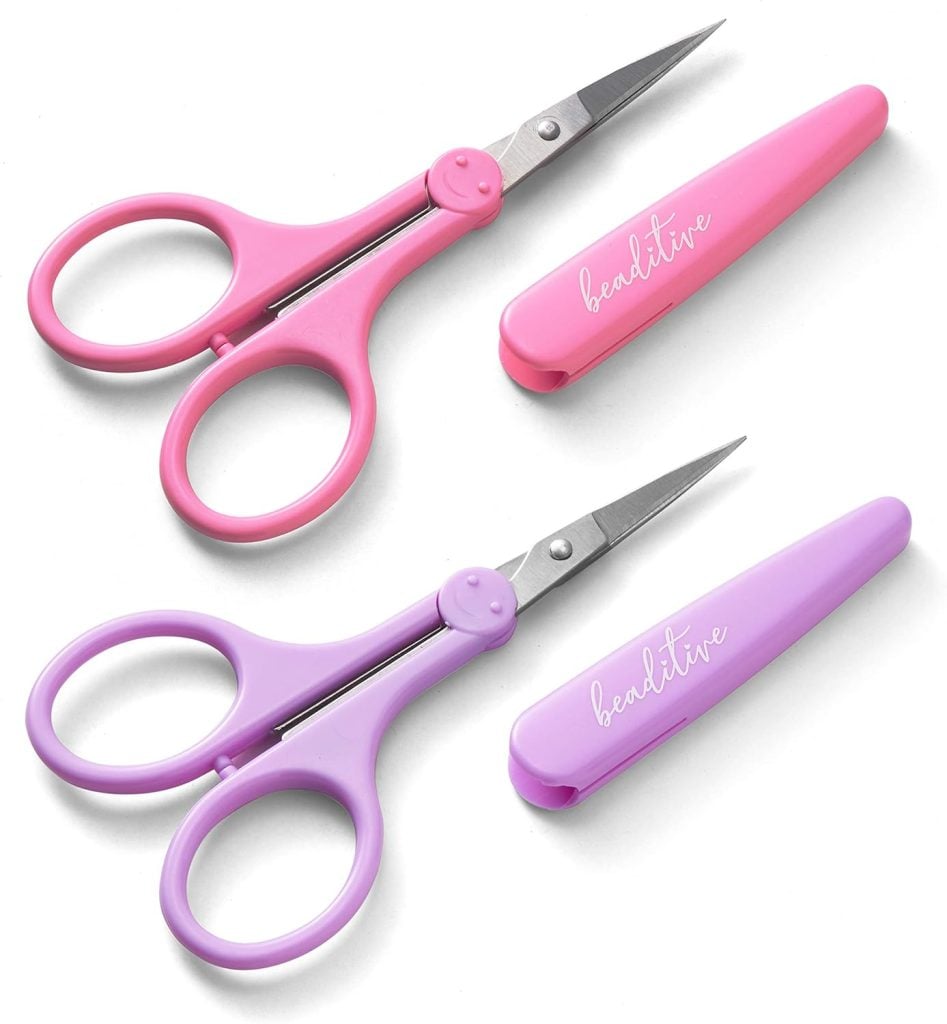Two pairs of small scissors, one pink and one purple, each with a matching protective cover labeled "beactive.