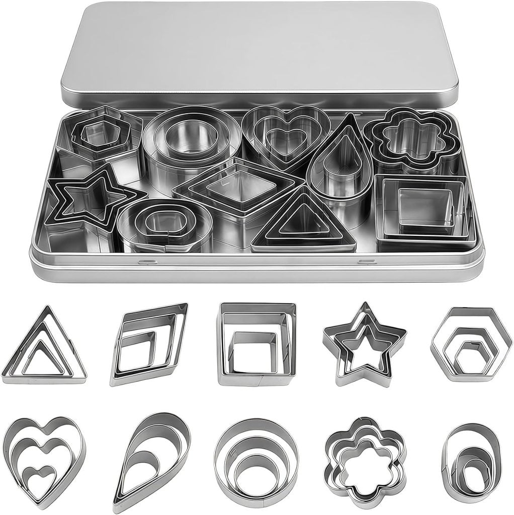 A metal tin containing various metal cookie cutters in different geometric and themed shapes, perfect for making cookies or crafting unique polymer clay charms, with the cutters displayed in front of the tin.