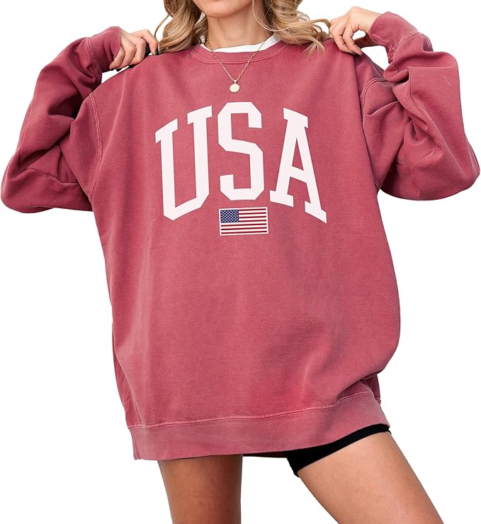 Person wearing an oversized maroon sweatshirt with "USA" and a small American flag printed on the front. Only the upper body and part of one leg are visible.