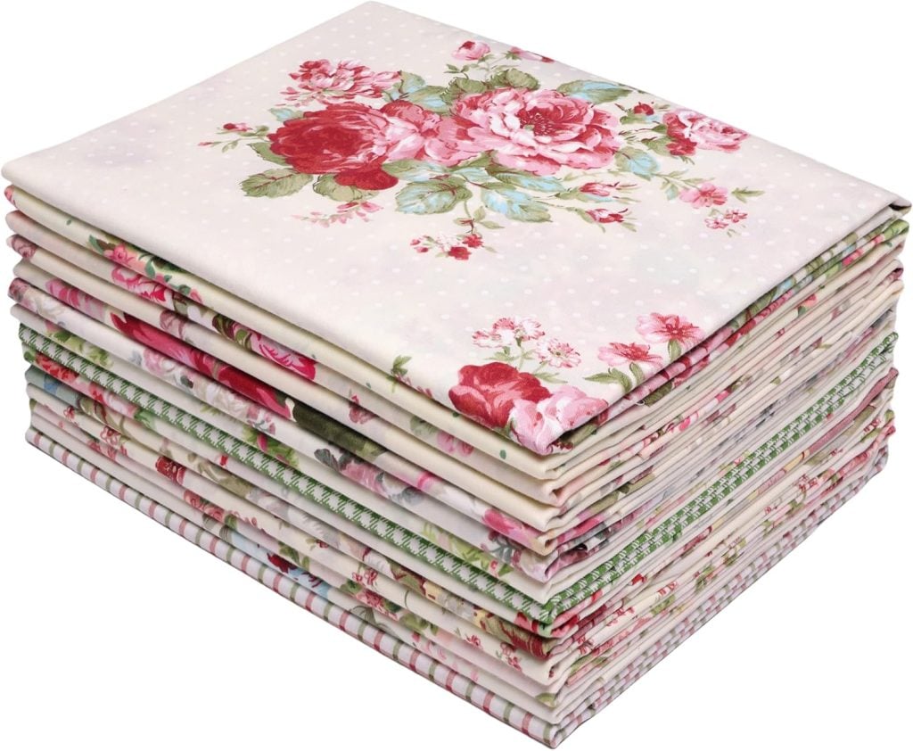 A stack of folded fabric pieces with various floral and patterned designs, predominantly featuring pink and red roses.