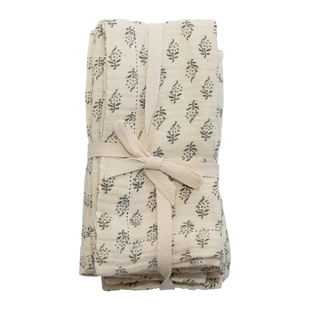 Folded cream-colored cloth with a small black leaf pattern, tied with a matching fabric ribbon.