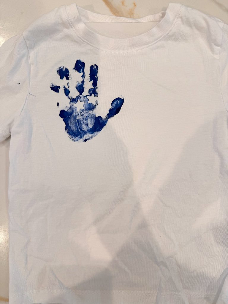 A white t-shirt with a blue handprint on the upper left side.
