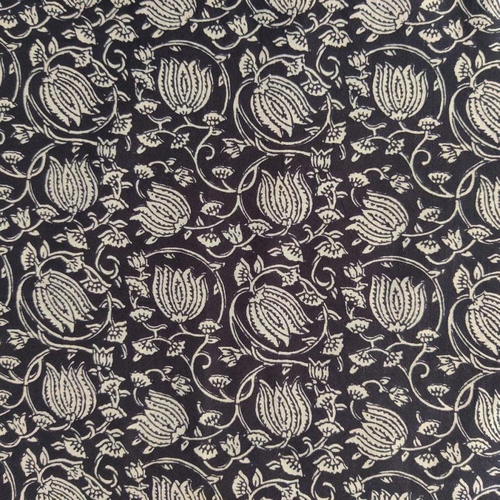 Black fabric with an intricate white floral pattern featuring repeating flowers and leaves arranged in a dense, symmetrical design.