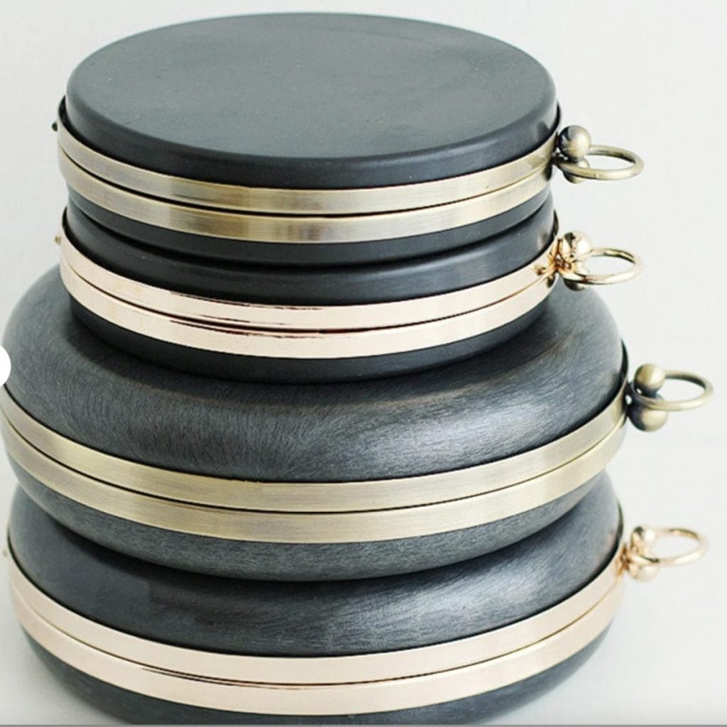 Three round, stacked black containers with metallic bands and circular handles are shown against a plain background.