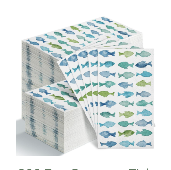 A stack of white paper napkins decorated with rows of blue and green fish illustrations, reminiscent of whimsical polymer clay charms. Four napkins are fanned out in front.