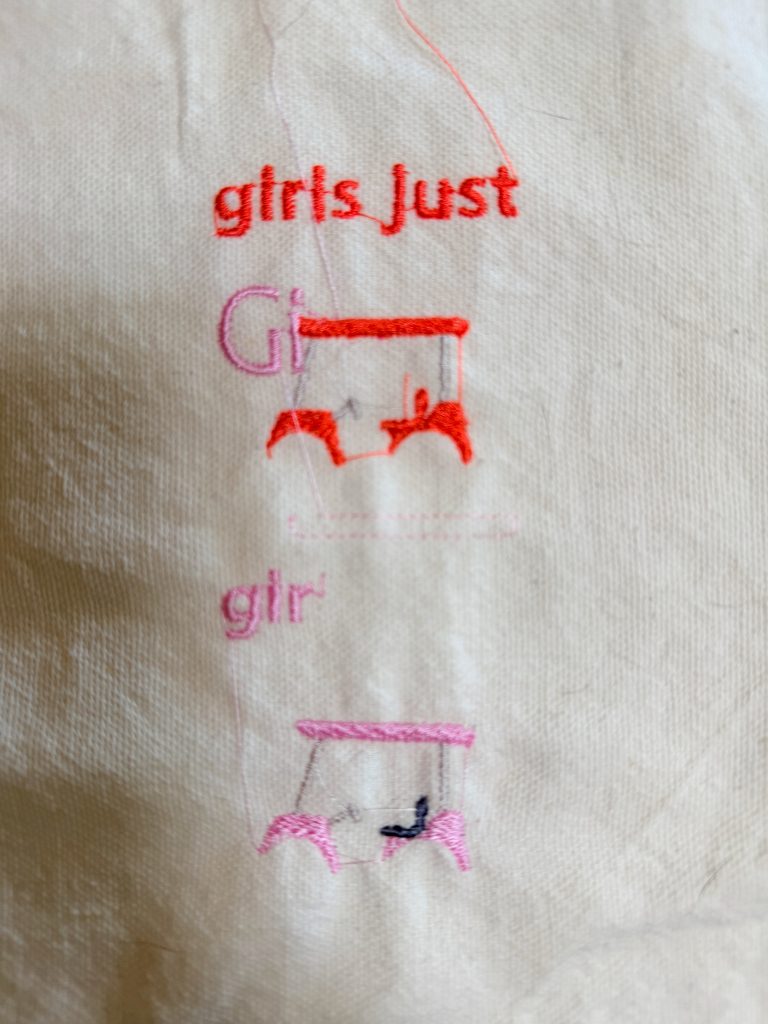 Two embroidered golf carts and partially stitched words "girls Just" and "gir" in shades of pink and red on a piece of white fabric.